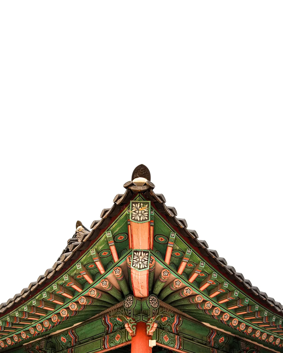 Upward view of the intricately painted roof eaves of a traditional Korean hanok at Namsangol Hanok Village in Seoul, framed against a bright overcast sky.